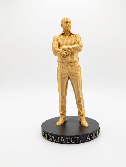 Statuetă auriu imprimată 3D a unui bărbat cu brațele încrucișate pe un soclu negru cu textul 'ANGAJATUL ANULUI'.